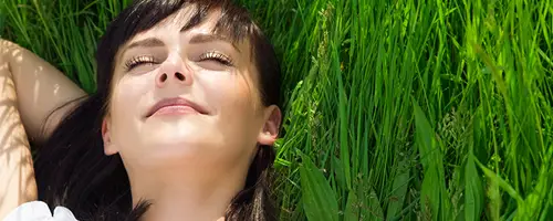 Imagen de una mujer relajada y sonriente tumbada en el campo.