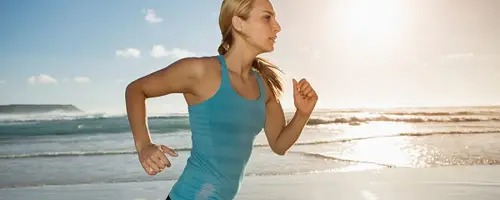 Imagen de una mujer deportista, corriendo por la playa.